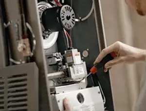 Furnace repair technician inspecting internal components and wiring in Durham, NC