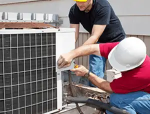 HVAC technicians repairing an outdoor AC unit on a rooftop in Durham, NC