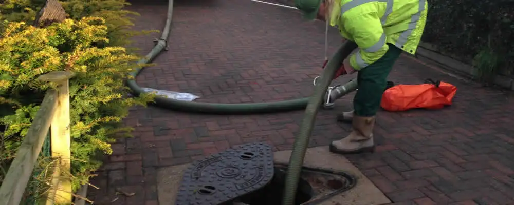 Septic tank cleaning technician servicing a septic tank with a vacuum hose in Durham, NC