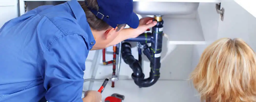 Plumber repairing under-sink drain pipes and fittings in Durham, NC